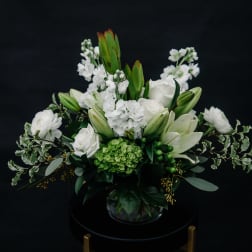White floral arrangement with lilies and roses in a glass vase