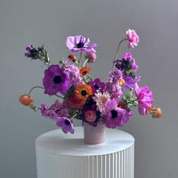 A small vase arrangement of purple, pink, and orange flowers