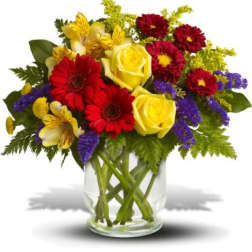 Bouquet of yellow roses, red gerberas, and purple filler in a glass vase