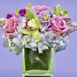 Pink roses and blue hydrangeas arranged in a clear glass vase
