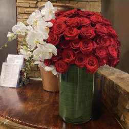 Large arrangement of red roses with white orchids in tall vases