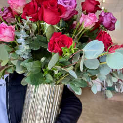 Bouquet of red, pink, and purple roses in a tall metallic vase