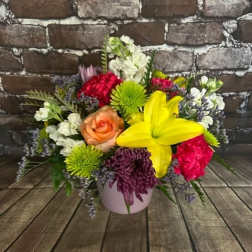 Mixed bouquet in a pink vase with a yellow lily and colorful blooms