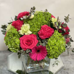Pink roses and gerbera daisy in a glass vase with green hydrangea