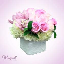 Pink roses and lilies arranged in a square vase