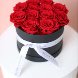 Red roses arranged in a black round box with a white ribbon