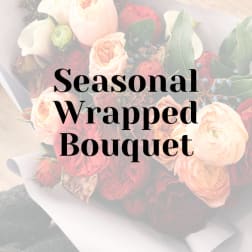 Wrapped bouquet of blush and red roses with greenery