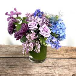 Purple and blue flowers arranged in a glass vase