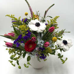 Mixed bouquet with tulips, gerbera daisies, and white anemones in a white vase