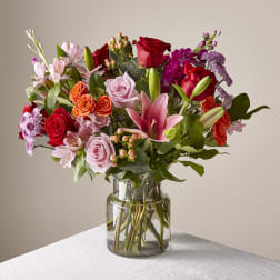 Mixed bouquet of roses, lilies, and alstroemeria in a glass vase