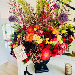 Large mixed floral arrangement in a black vase with tall stems