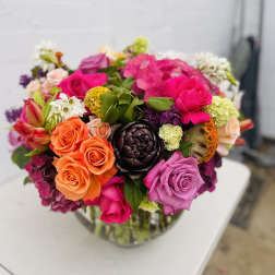 Bright mixed bouquet of roses and other flowers in a glass vase