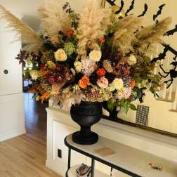 Large autumn floral arrangement in a black urn with pampas grass and mixed blooms