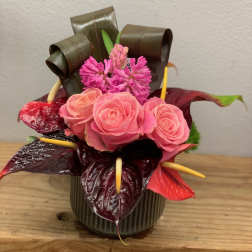 Pink roses and magenta flowers arranged in a small vase