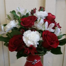 Red roses and white carnations in a red vase with a glittery heart pick