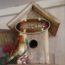 Wooden birdhouse with a decorative bird and "welcome" sign