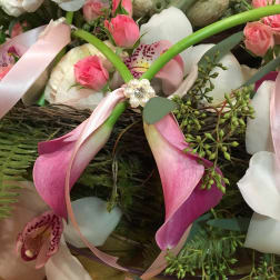 Pink calla lilies, spray roses, and orchids with pink ribbon and pearls in a lush mixed arrangement