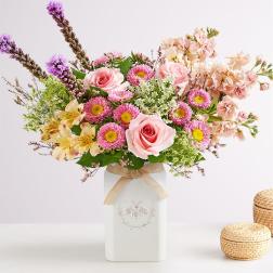 Pink and peach mixed bouquet in a white vase with a ribbon