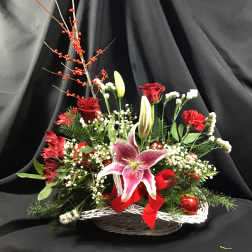 Basket arrangement with red roses, pink lilies, and holiday berries