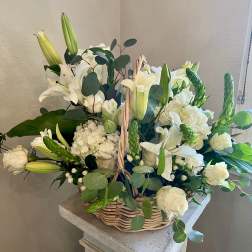 White lilies and roses arranged in a wicker basket