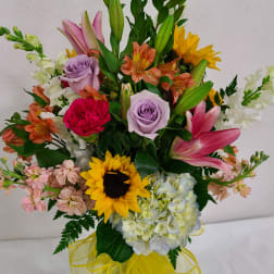 Mixed bouquet with sunflowers, lilies, roses, and hydrangeas in a glass vase
