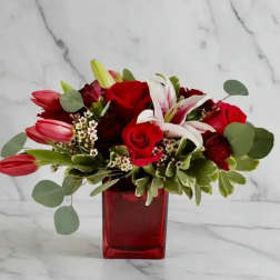 Red roses and lilies in a red glass vase