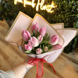 Pink tulip bouquet wrapped in pale paper with a red ribbon