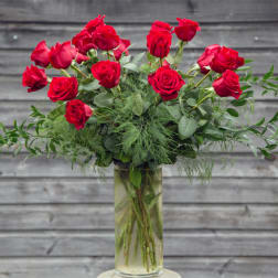 Red roses arranged in a clear glass vase with airy greenery