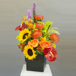 Bright mixed floral arrangement in a black square vase