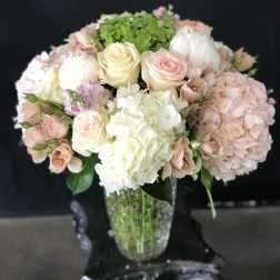 Pastel bouquet of roses and hydrangeas in a clear glass vase