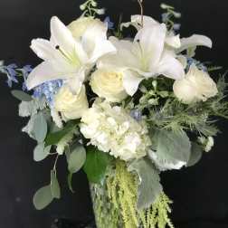 White lilies and roses in a glass vase with blue accents