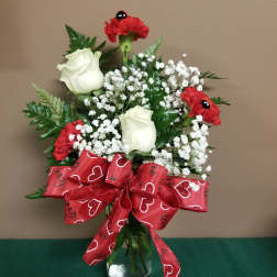 Bouquet of white roses and red carnations in a glass vase with a red ribbon