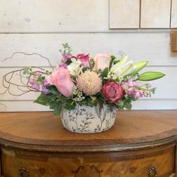 Pink and white floral arrangement in a patterned ceramic container