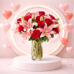 Red roses and pink lilies in a clear glass vase with heart balloons