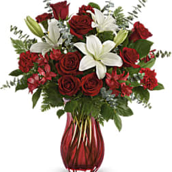 Red roses and white lilies arranged in a red glass vase