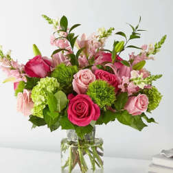 Pink roses and lilies arranged in a clear glass vase
