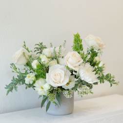 White rose arrangement in a gray vase with green accents