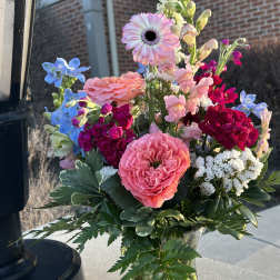 Mixed bouquet in a clear glass vase with pink, blue, and white blooms