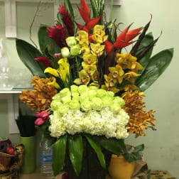 Tall tropical arrangement with orchids, calla lilies, and hydrangeas in a black vase
