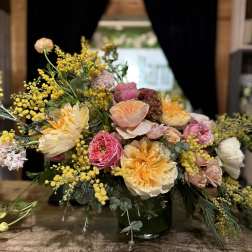 Mixed bouquet of peach, pink, and yellow flowers in a glass vase