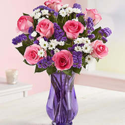 Pink roses and white-purple filler flowers in a purple glass vase