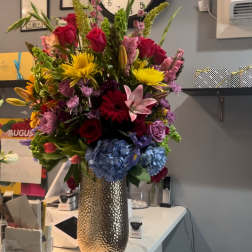 Tall mixed bouquet in a metallic vase with roses, lilies, and hydrangeas