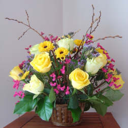 Yellow roses and daisies in a wicker basket with pink filler flowers