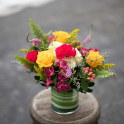 Colorful bouquet of roses and mixed flowers in a striped glass vase