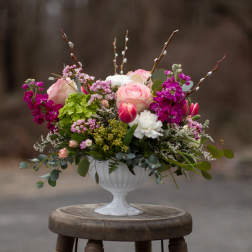 Pink and white floral arrangement in a white pedestal vase