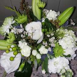 Compact arrangement of white roses, lilies, and carnations with green accents