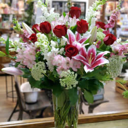 Red roses and pink lilies in a clear glass vase
