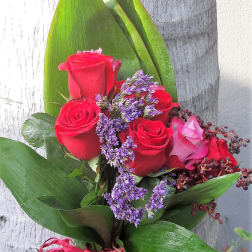 Bouquet of red roses with purple filler and broad green leaves