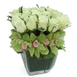White roses and green orchids in a glass vase
