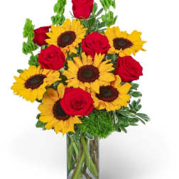 Bouquet of red roses and yellow sunflowers in a glass vase